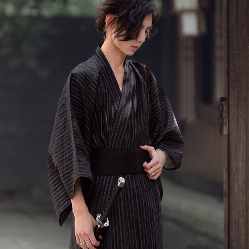 Póngase un Kimono Japones de Hombre para hombre y luzca el estilo tradicional samurái. El hombre sostiene un cinturón obi negro y una katana.