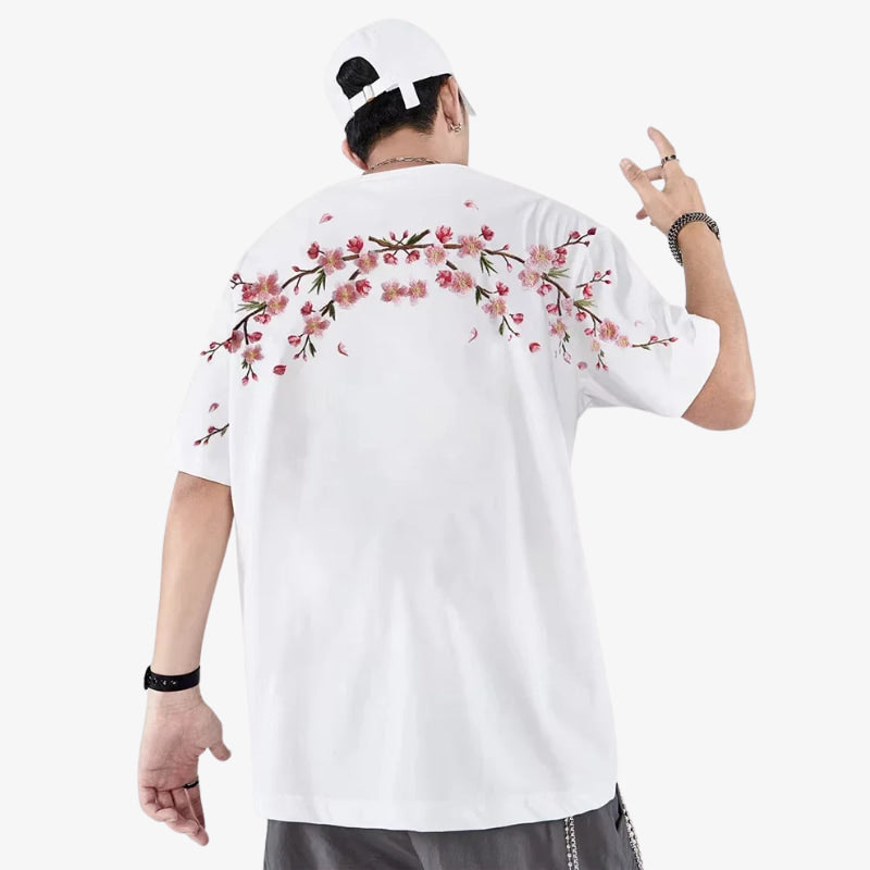 Persona con camisa sakura blanca bordada con motivos florales en la espalda, posando sobre un fondo blanco.