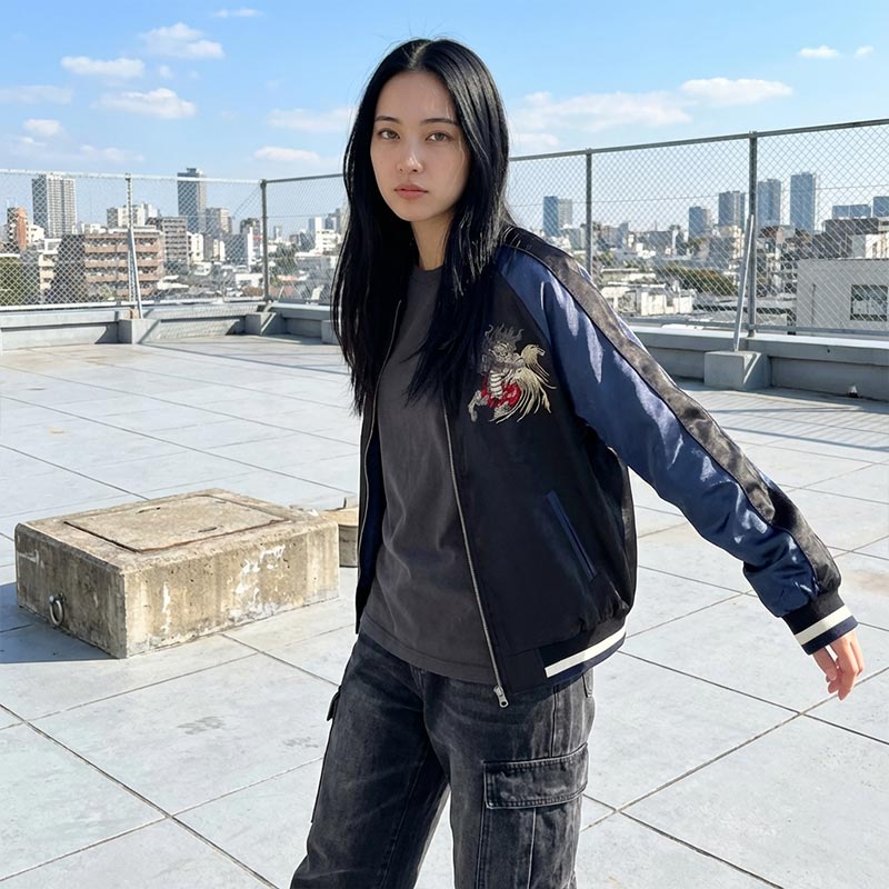 Persona con chaquetas souvenir negra y azul con bordado en una azotea con vista a la ciudad
