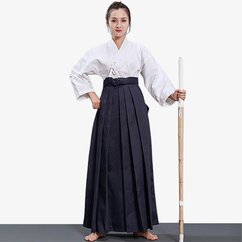 Una artista marcial japonesa vestida con hakama mujer, un keikogi blanco y sosteniendo un shinai de madera