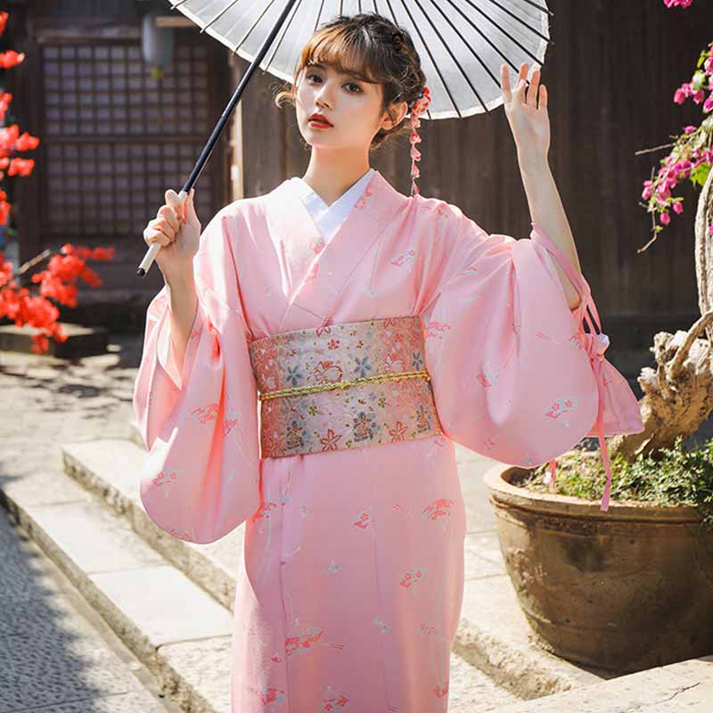 Mujer vestida con kimono japonés y obi sakura atado con motivos florales bordados, sosteniendo una sombrilla