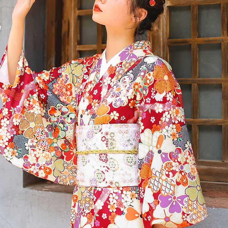 Mujer luciendo un kimono rojo con cinturón obi blanco bordado con motivos sakura