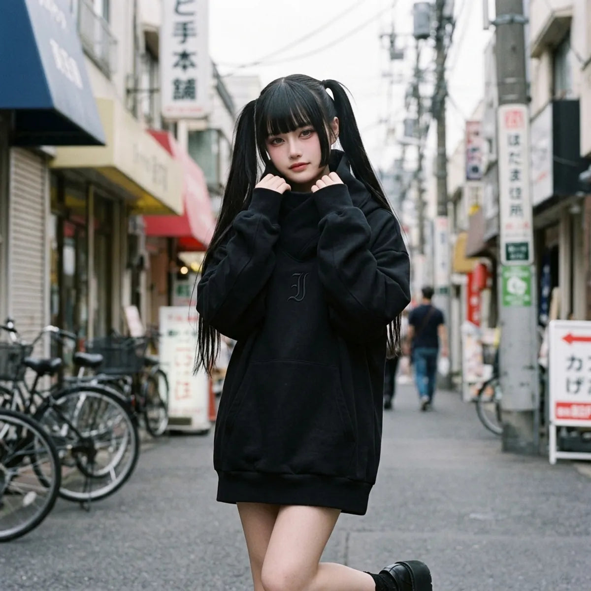 Sudadera oversized negra llevada por una mujer en Harajuku, con el cuello tipo chimenea envolviendo el cuello