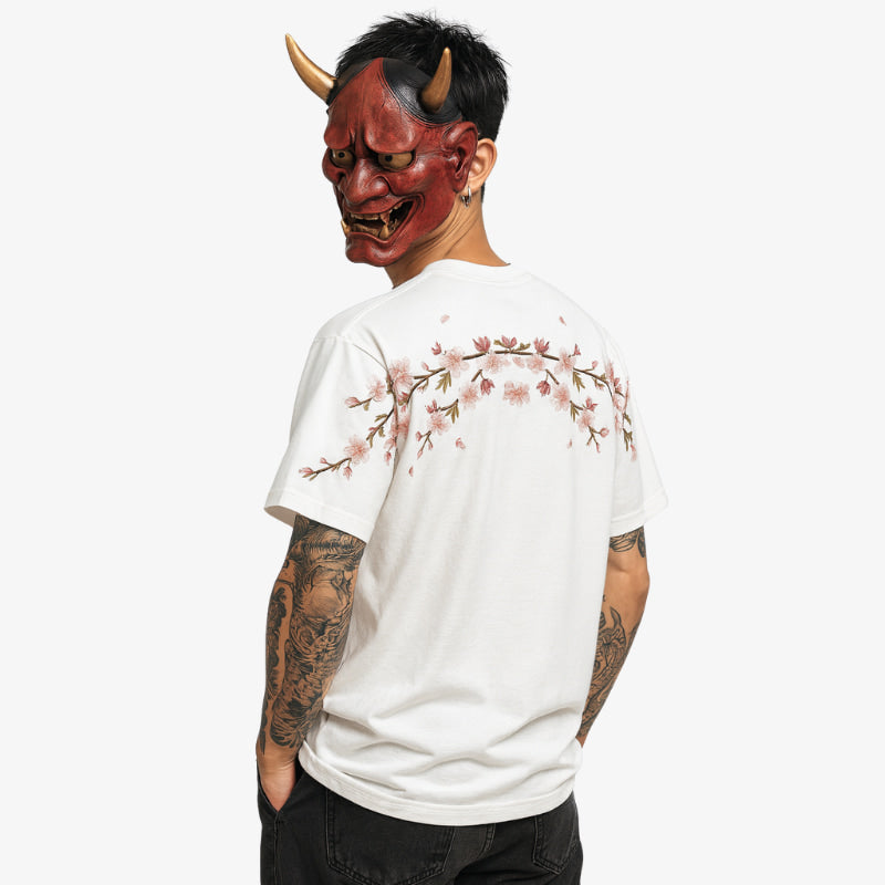Persona con una Camisa Bordada Hombre blanca con un diseño de flores de cerezo y una máscara roja de diablo sobre fondo blanco