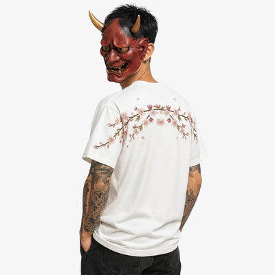 Persona con una Camisa Bordada Hombre blanca con un diseño de flores de cerezo y una máscara roja de diablo sobre fondo blanco