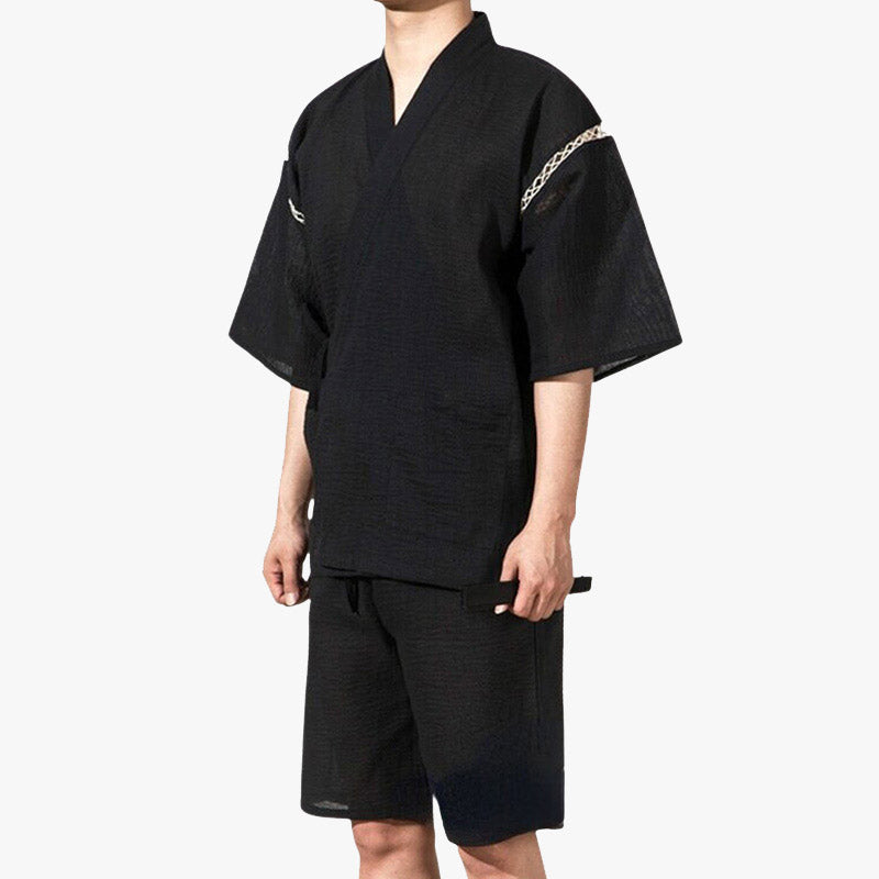 Una persona con ropa Jinbei Japones tradicional, que es un conjunto de kimono corto, en color negro con rayas finas y detalles decorativos en las mangas.