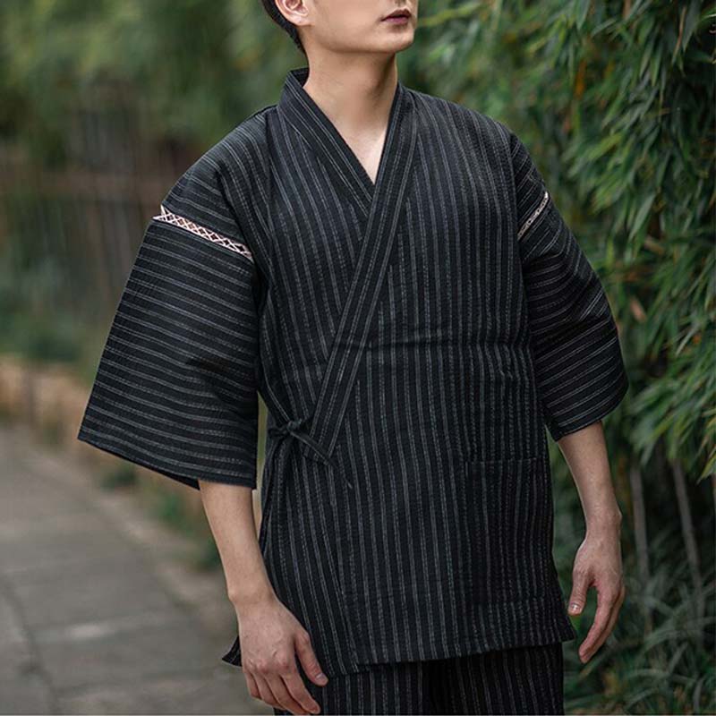 Un hombre vestido con un Jinbei Pijama Hombre Japones. El kimono ligero está confeccionado en algodón. El color es negro con rayas.