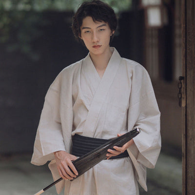 Explora nuestra elegante colección de ropa conKimono Japones Blanco​ para hombre, diseñados para ceremonias tradicionales y eventos formales modernos. El hombre también lleva un cinturón samurai obi.