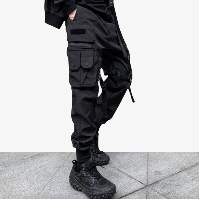 Pantalones techwear negros de ropa técnica para hombre con un conjunto urbano totalmente negro.