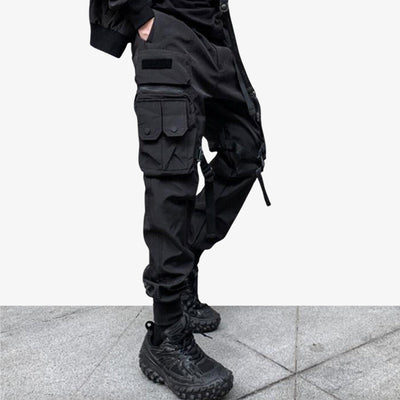 Pantalones techwear negros de ropa técnica para hombre con un conjunto urbano totalmente negro.