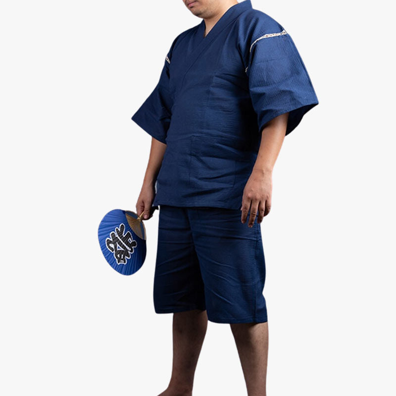 Este kimono jinbei est un pijama japonesa tradictional hombre. El abanico uchiwa que lleva en la mano tiene un kanji impreso en la tela.