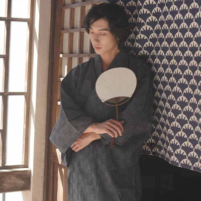 Mira la foto real del samurái yukata tradicional japonés para hombre por detrás. Sostiene un abanico japonés blanco Uchiwa en las manos.