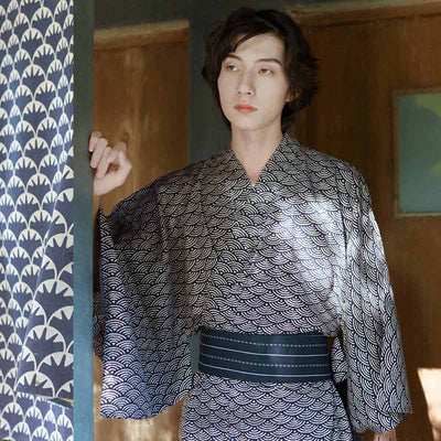 Un hombre japonés está de pie. Viste un Seigaiha kimono. El kimono es de algodón ligero y lleva un cinturón obi japonés.