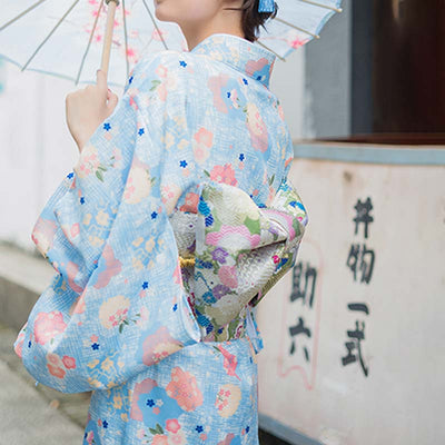 Mujer en una calle de Japón vistiendo un kimono con estampado floral y cinturón obi