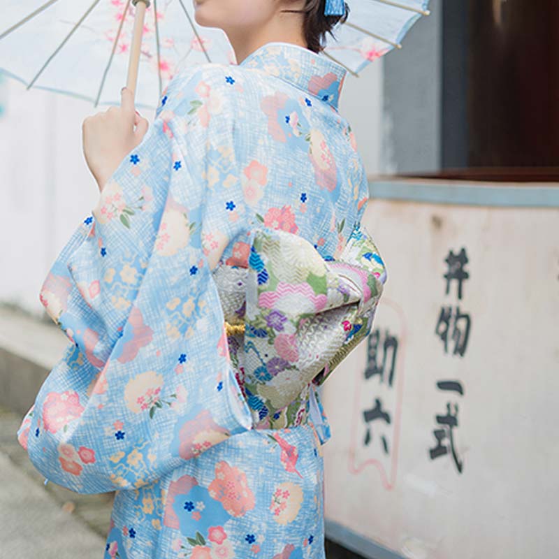 Mujer en una calle de Japón vistiendo un kimono con estampado floral y cinturón obi