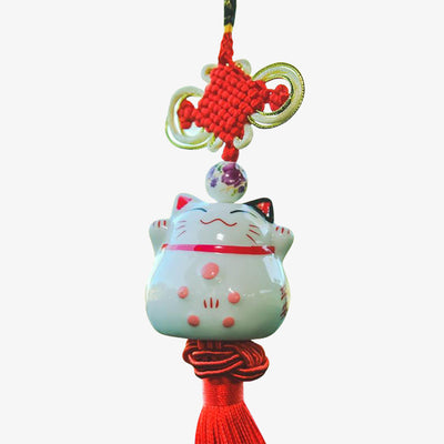 Amuleto Maneki Neko de cerámica blanca colgado en el retrovisor con hilo rojo