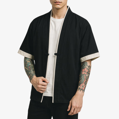 Persona con una chaqueta estilo kimono negro con ribetes blancos sobre fondo blanco
