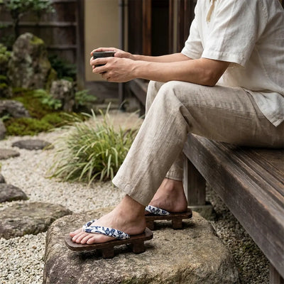 Sandalias geta llevadas con calcetines tabi por un hombre sentado en un jardín japonés