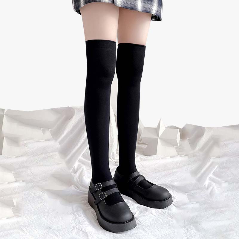 Una chica lleva un par de calcetines largos de moda japonesa con zapatos de colegiala y una falda de cuadros.