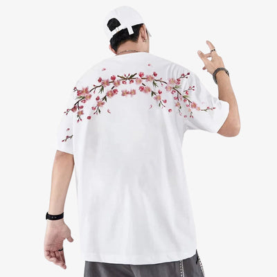 Persona con  camisa sakura blanca bordada con motivos florales en la espalda, posando sobre un fondo blanco.