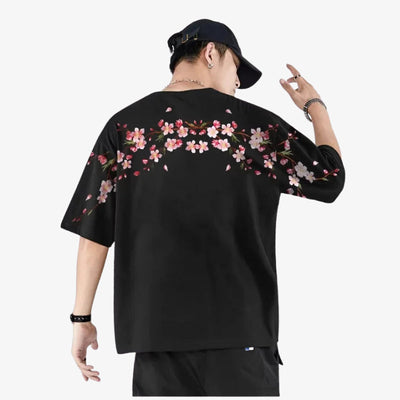 Persona con una camiseta sakura humbre de color negra de estilo urbano con diseños florales sobre fondo blanco.