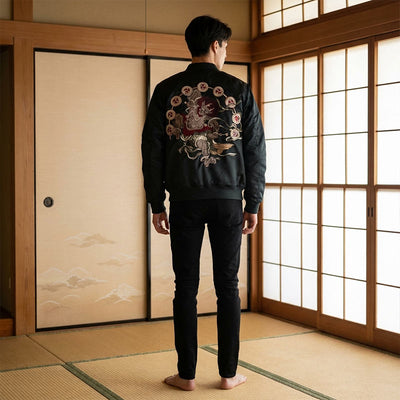 Persona con una chaqueta souvenir japonesa negra con diseño de Fujin bordado en una habitación tradicional