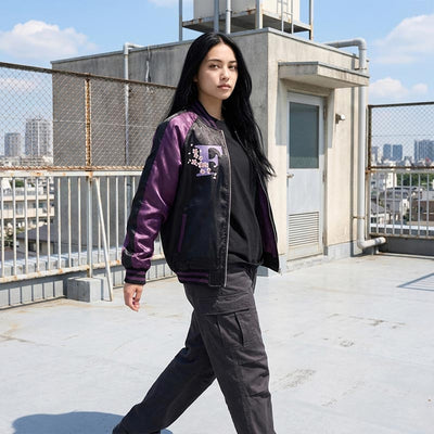 Mujer con chaqueta souvenir morada en la azotea de un instituto japonés con Tokio de fondo