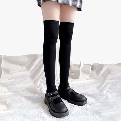 Chica con calcetines tabi largos japoneses, zapatos de colegiala y falda de cuadros