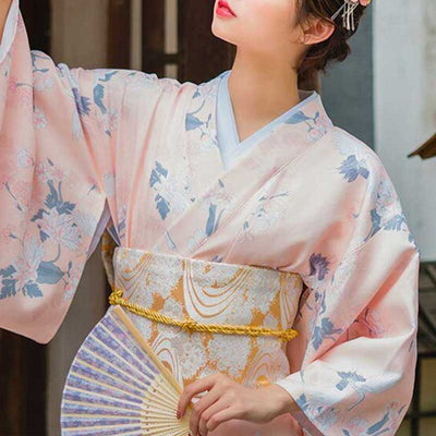 Mujer con cinturón obi tipo corsé sujetando un kimono blanco con símbolos japoneses