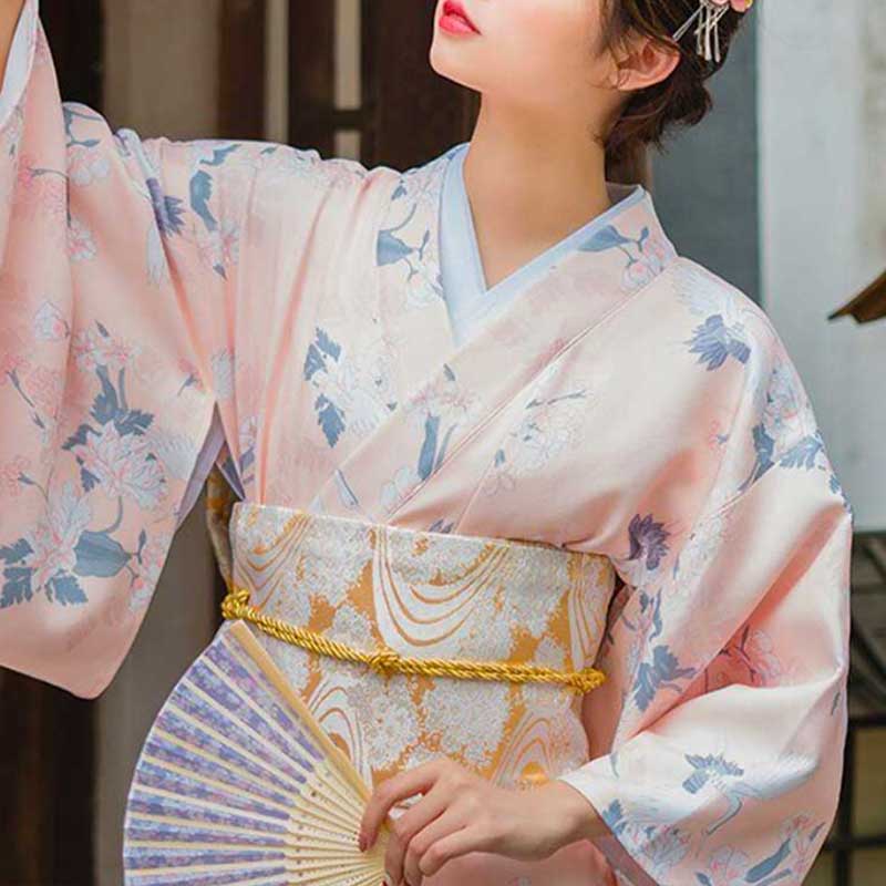 Mujer con cinturón obi tipo corsé sujetando un kimono blanco con símbolos japoneses