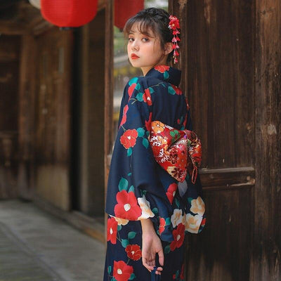 Cinturón obi para kimono japonés con flores rojas de ume sobre tela suave. La mujer lleva el kimono largo cerrado con un obi rojo y un kanzashi en el pelo