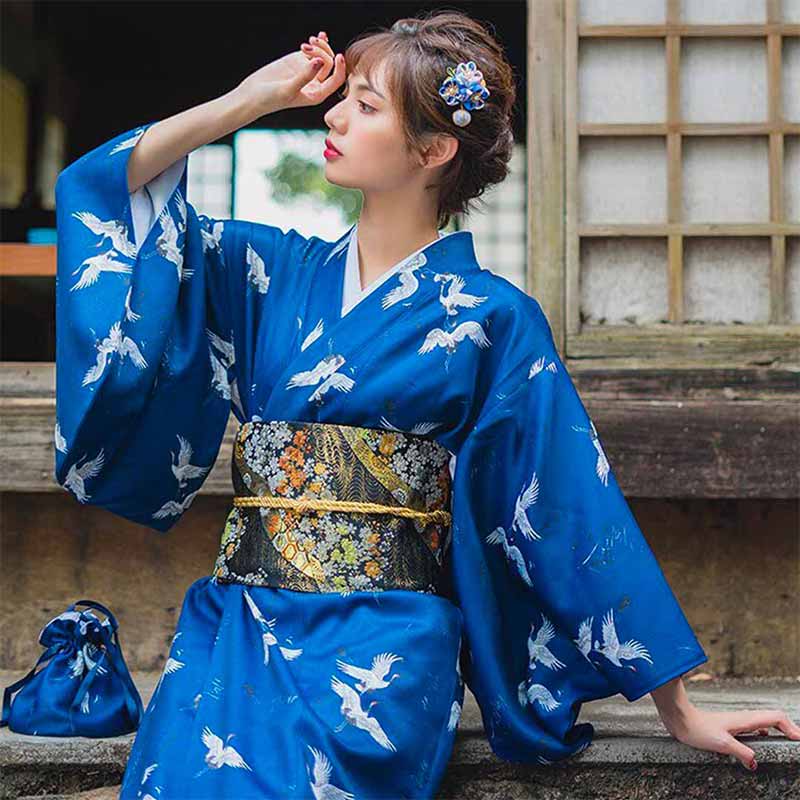 Cinturón obi floral atado a un kimono azul con grullas tsuru