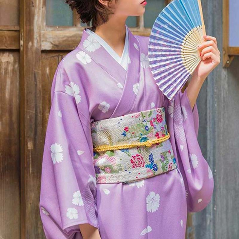 Mujer atando un cinturón obi para sujetar su kimono tradicional