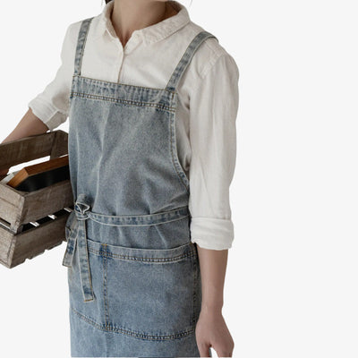Delantal vaquero clásico en azul, con tirantes cruzados y un gran bolsillo frontal, que combina el diseño tradicional japonés con la durabilidad moderna
