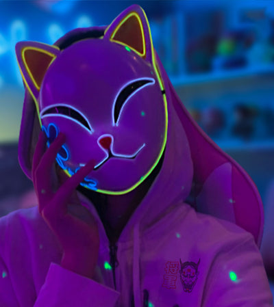 Una mujer lleva la demon slayer anime mascaraque simboliza al zorro demoníaco japonés. La máscara kistune brilla en la oscuridad.