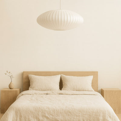 Dormitorio beige con cama, mesillas de noche y una lámpara colgante japonesa