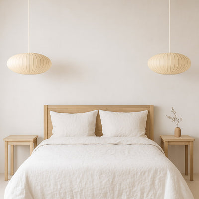Dormitorio con cabecero de madera, ropa de cama blanca y lámparas de papel japonesas colgantes