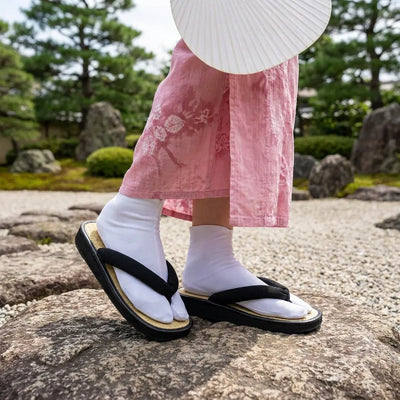 Manos de artesano tallando sandalias de madera japonesas