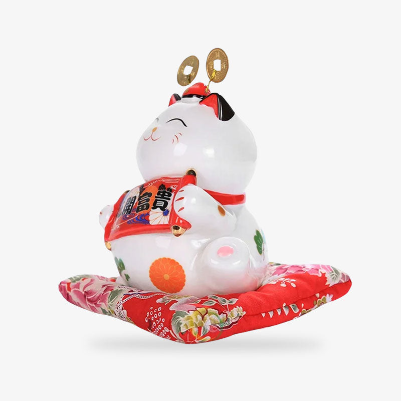 Gato de la suerte japonés de cerámica blanca sobre cojín rojo