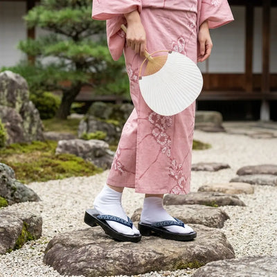 Sandalias geta llevadas con kimono rosa en jardín japonés