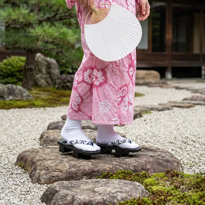 Sandalias geta llevadas con un kimono rosa en un jardín japonés