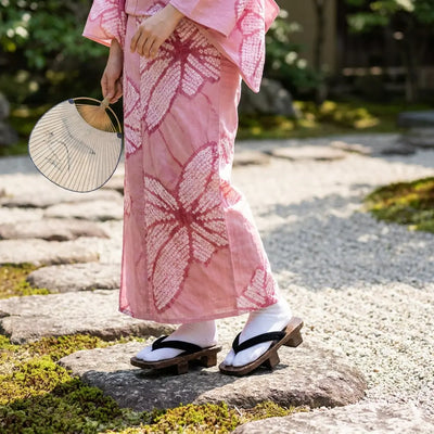 Geta mujer llevado con un kimono rosa en un jardín japonés