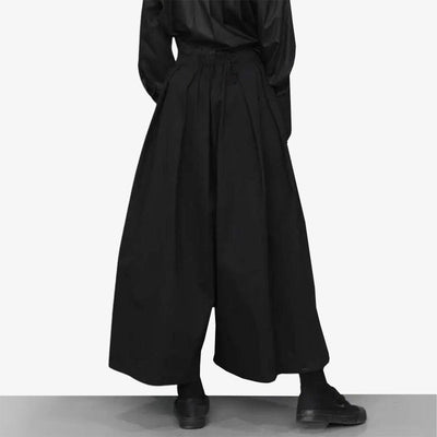 Este moderno pantalones es un hakama mujer negro. La mujer lleva zapatos negros para un estilo urbano y techwear japonés.