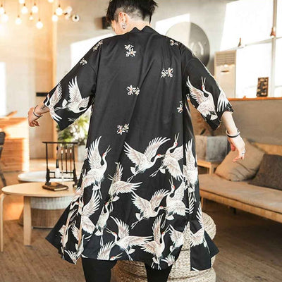 Hombre luciendo un haori negro con motivos de grullas blancas y flores de cerezo
