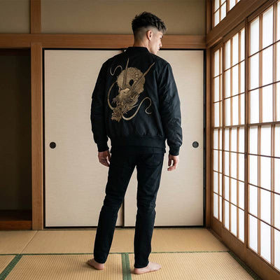 Hombre con una chaqueta bomber japonesa negra con un diseño de dragón bordado en una sala tradicional japonesa