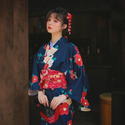 Kimono flores ume para mujer, con hermosos estampados florales. El kimono largo se cierra con un cinturón obi y la mujer lleva un kanzashi en el cabello