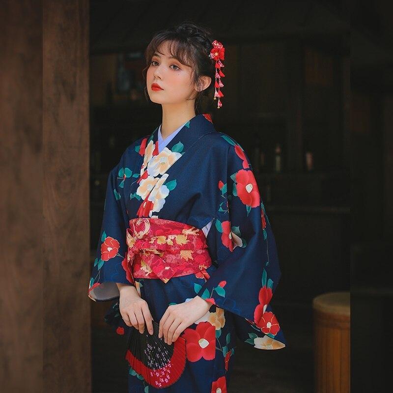 Kimono flores ume para mujer, con hermosos estampados florales. El kimono largo se cierra con un cinturón obi y la mujer lleva un kanzashi en el cabello