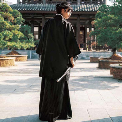 Kimono japonés tradicional para hombre en un jardín junto a un templo