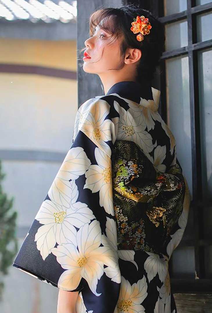 Kimono tradicional japonés con estampado floral amarillo, complementado con un kanzashi de flor en el cabello