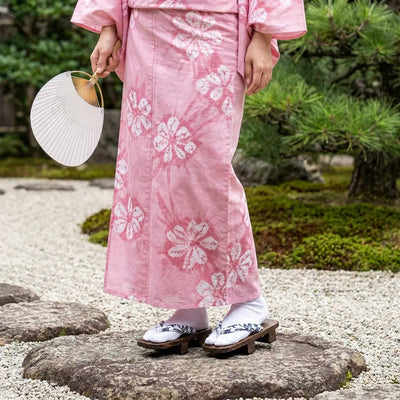 Sandalias geta llevadas con un kimono rosa en un jardín japonés